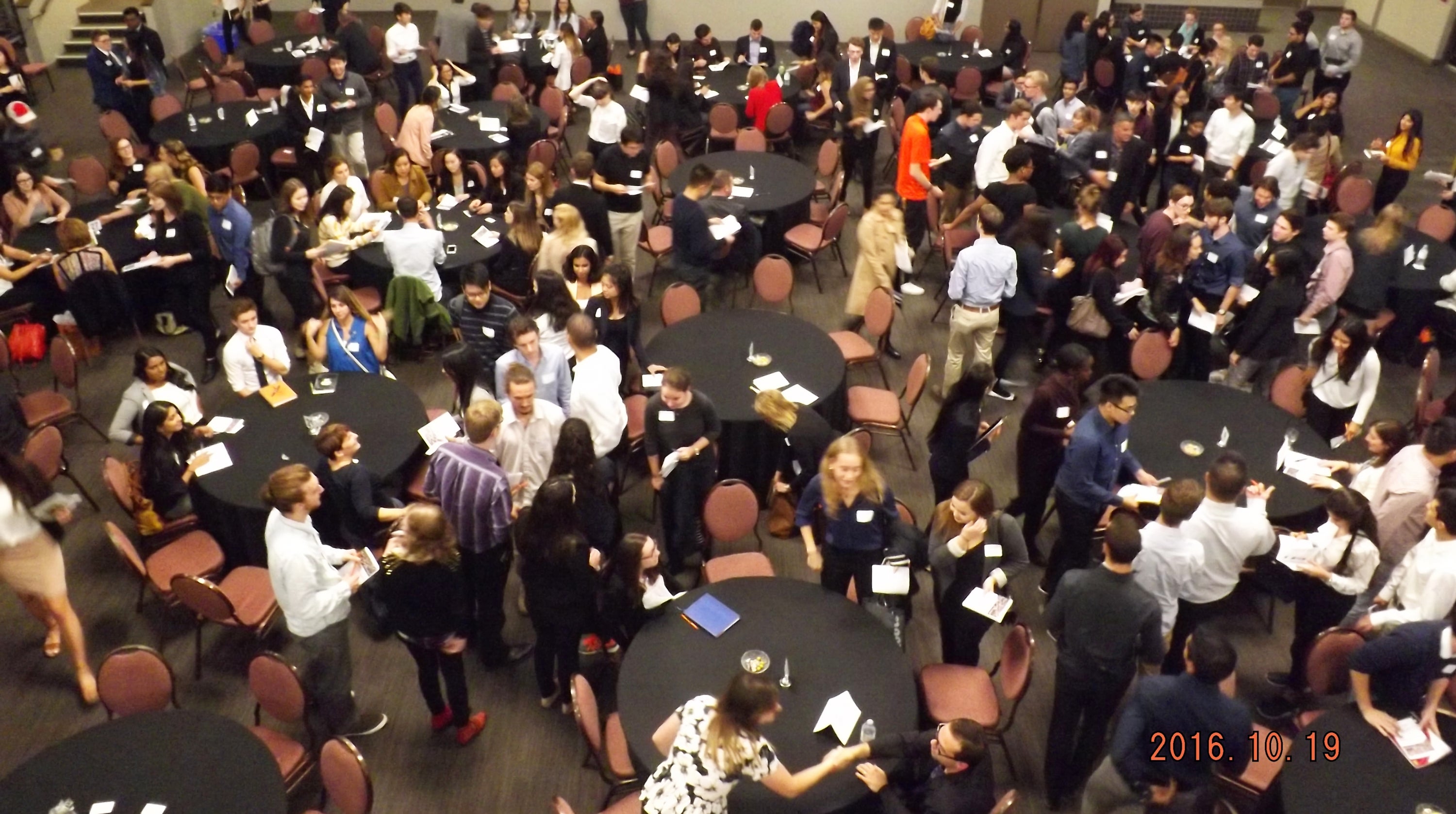 large group of students networking around tables