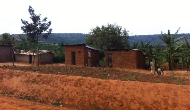 Ugandan dirt field and huts in background