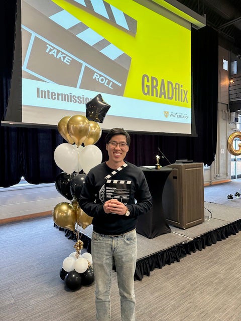 Brian Kim standing in front of podium and balloons.
