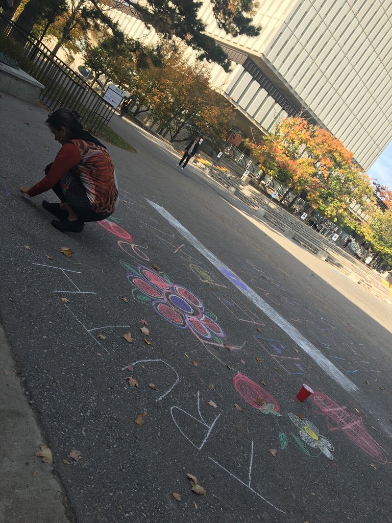 Students drawing with chalk on the pavement near the Dana Porter library