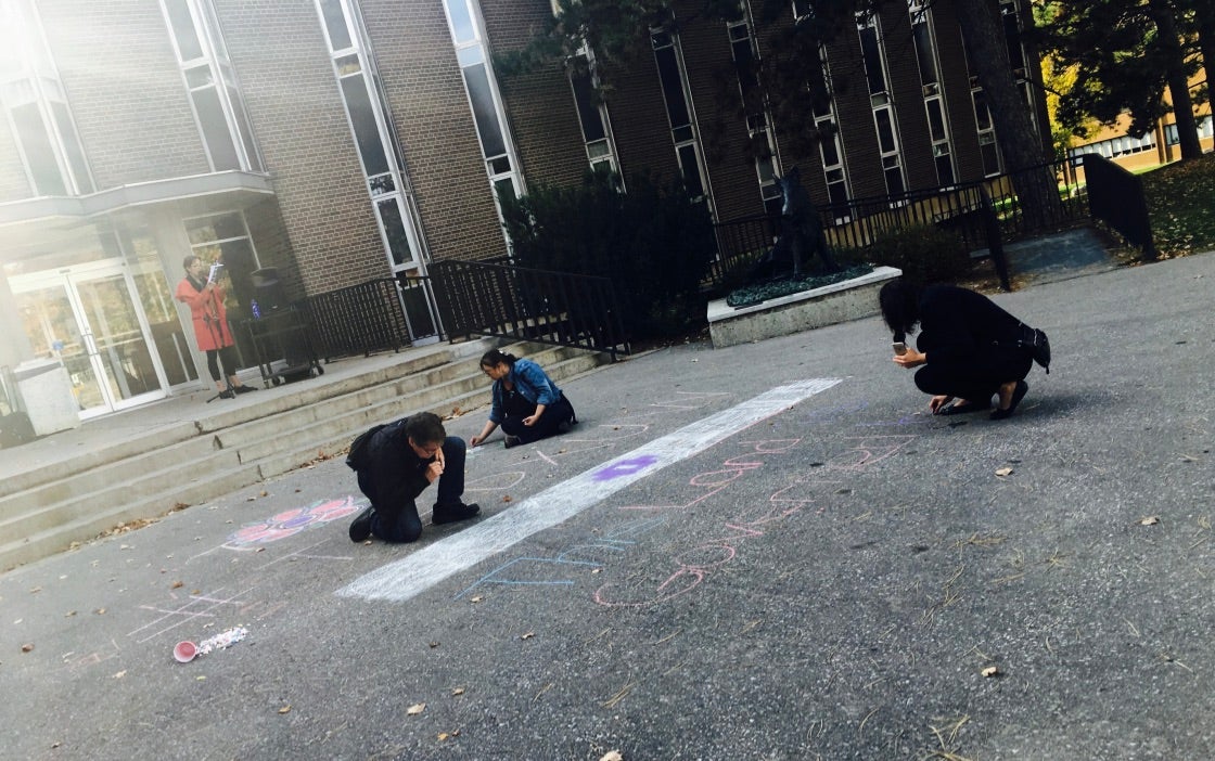 Students work on chalk drawings in the quad outside the Modern Languages building