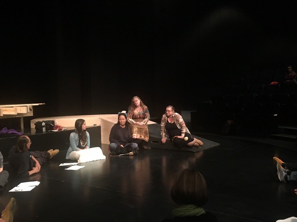 A group of students on a sparsely lit stage in the Modern Languages theatre