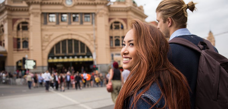 Young adults siteseeing outside a historic building in Melbourne. 
