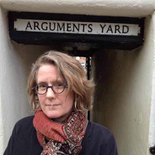 Jennifer Saul standing in a corridor beneath an old fashioned sign that says Arguments Yard