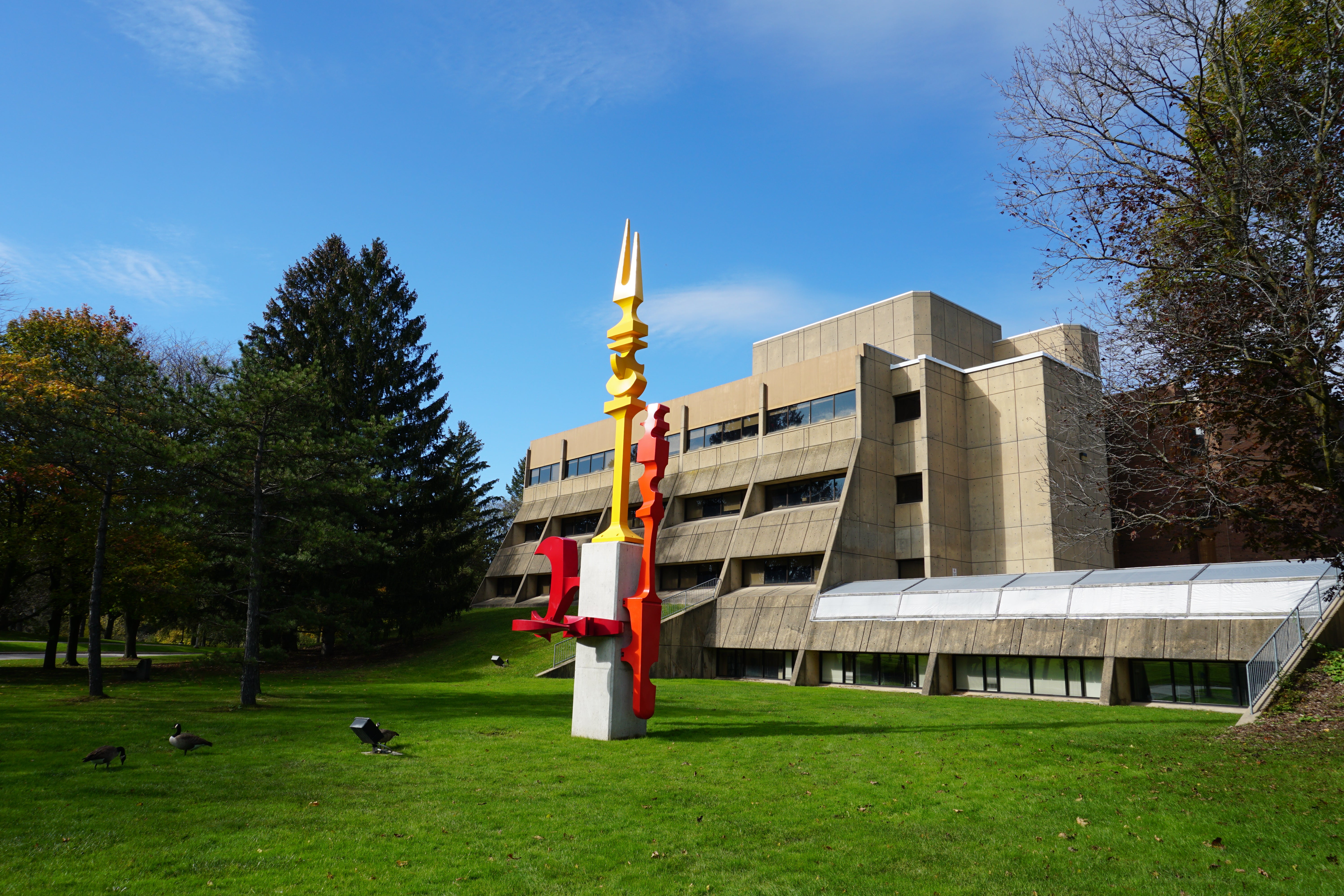 Modern concrete building with coloured steel sculpture on front lawn