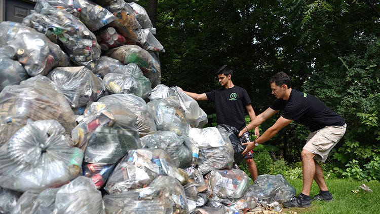 Dillon Mendes and Sam Demma build a tall pile of garbage bags