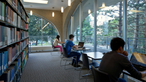 Students working on their laptops in Dana Porter library near a bookshelf