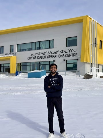 Student in front of building that says City of Iqaluit Operations Centre