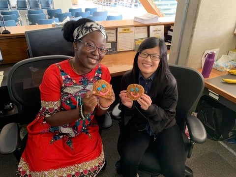 two staff members smiling holding smile cookies