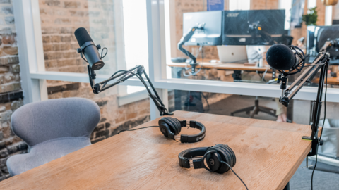 Microphone and over the ear headphones set up on a desk in a recording studio for podcasts