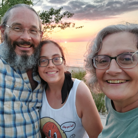 Scott and Linda Davis with daughter standing in front of body of water.