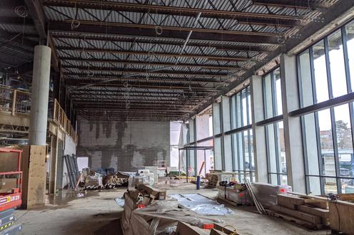 A large space under construction with exposed beams, wiring, and concrete floors.