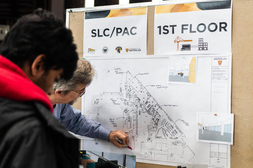 Students look at display boards with floor plans for the SLC/PAC expansion.