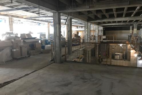 construction of new fitness space, concrete floor, exposed beams. Boxes along the left and yellow construction fence.