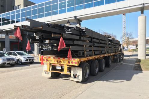 Flatbed truck with large steel beams parked under the bridge between MC and M3