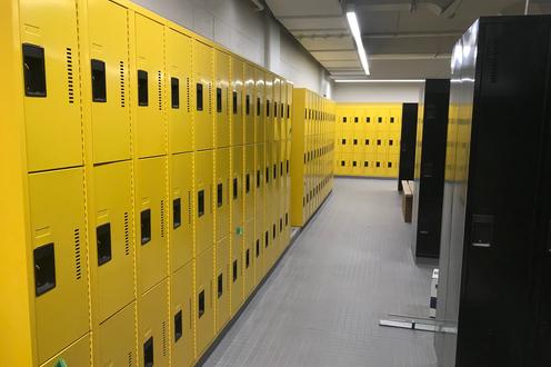 Rows of bright yellow lockers on the left and black lockers on the right in the renovated PAC men's change room.