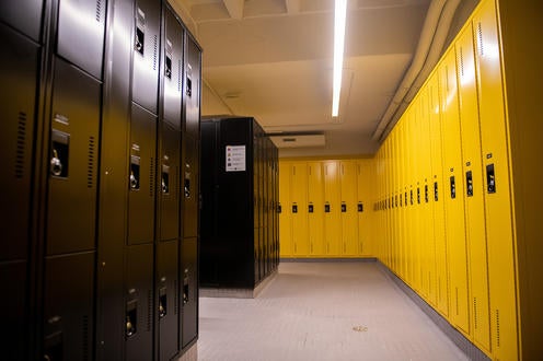 Smaller rows of black lockers on the right and yellow full size floor to ceiling lockers on the right.