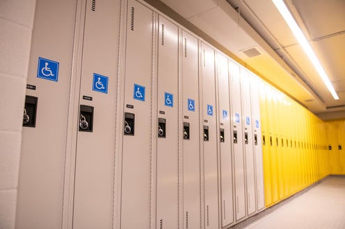 A series of white lockers with wheel chair accessibility stickers.