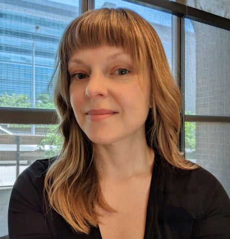 headshot of a person smiling with medium hair, a fringe and black top