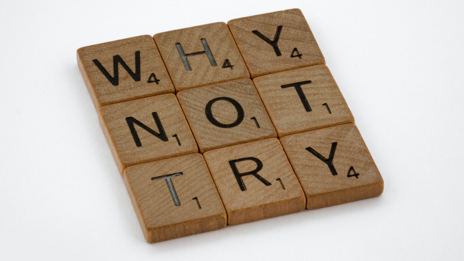 Scrabble tiles spelling out "Why not try"