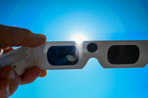 Pair of eclipse glasses being held in front of the Sun