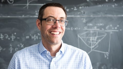 Will Percival in front of a blackboard with equations and diagrams