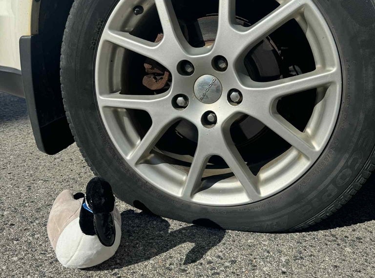 Toy goose sitting next to a flat tire