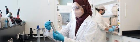 Showing students and professor in a lab setting wearing masks due to COVID-19 restrictions.