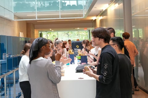 Students standing around a long reception table. 