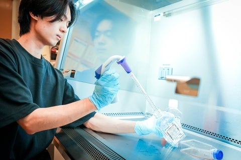 Student pipetting under a fume hood.