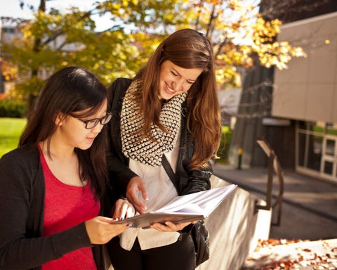 link, Two students studying outside in the Fall on Waterloo main campus.