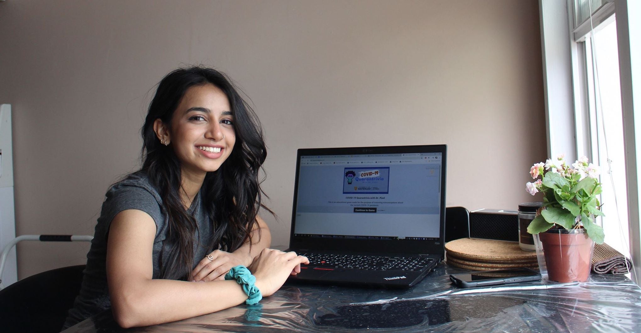 Ridhi Patel sits next to laptop with covid trivia game on the screen.
