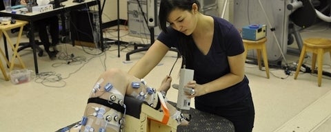Lab member applies force to subject's foot to test ankle flexibility.