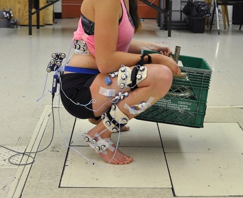 Participant at end range of knee flexion during squat with weighted crate