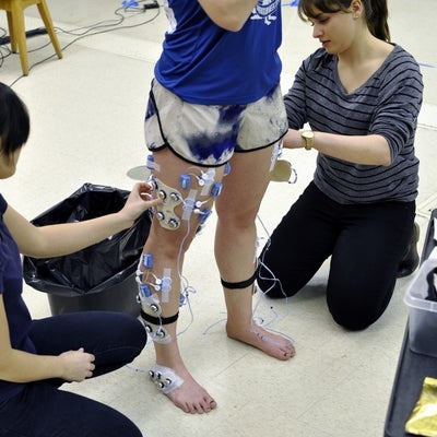 Two researchers instrumenting a participant's lower limb