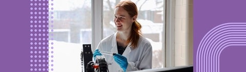 Student wearing a lab coat and holding test tube 