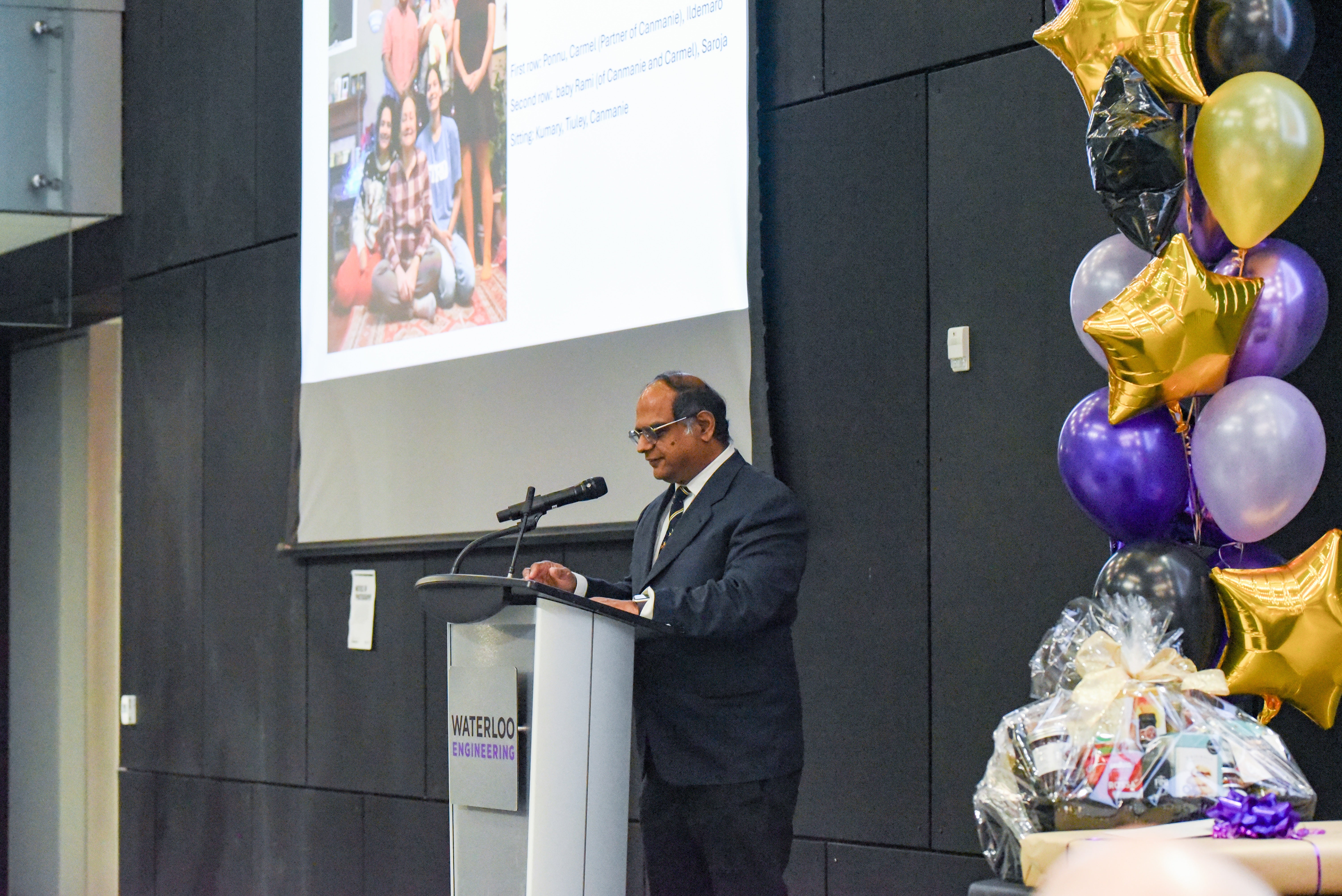 Ponnu providing his own speech with a photo of his family on the screen 