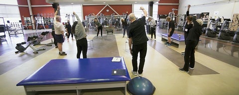 Adults exercising in gym.