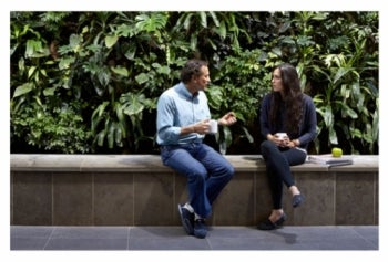 A man and woman have a conversation in front of a living wall in EV3.