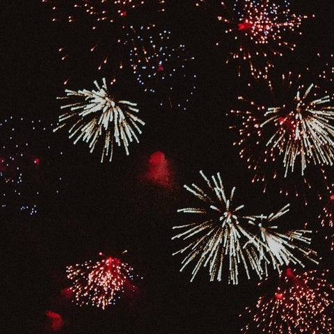 Red and white fireworks explode in a night sky