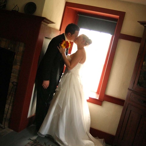 A couple, in wedding attire, stand by a Brubacher House window