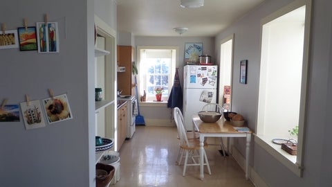 the brubacher house kitchen, more modernized, with white paint. Family photos on the fridge in the back corner. 