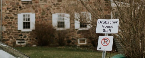 A sign that indicates Brubacher House staff parking, with a view of the house outside