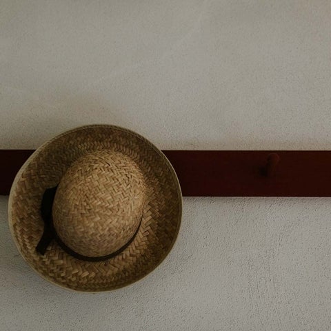 A straw hat hangs on a hook