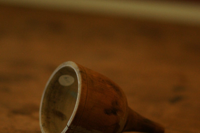 A wooden funnel, shaped like a bell, sits on it's side on a wooden counter
