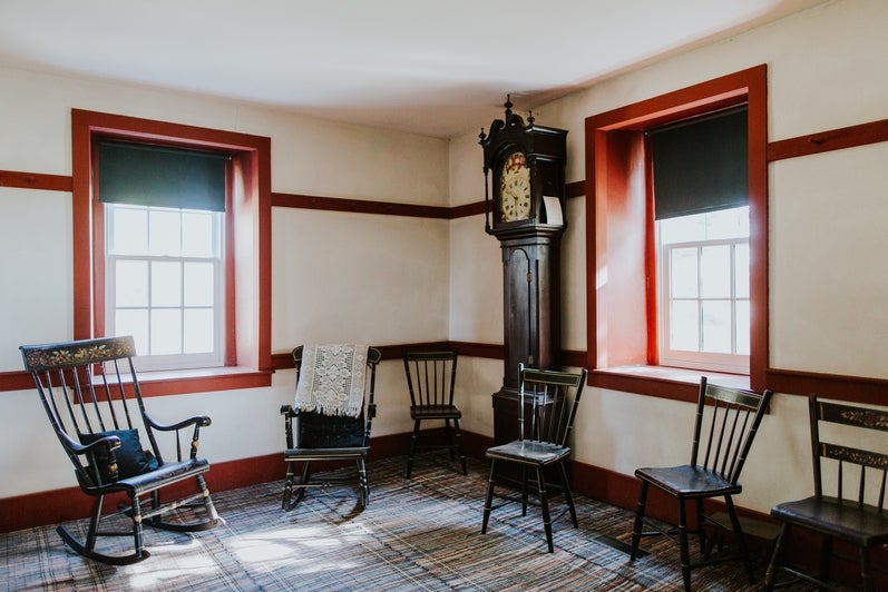 A room with various wooden chairs, and a grandfather clock