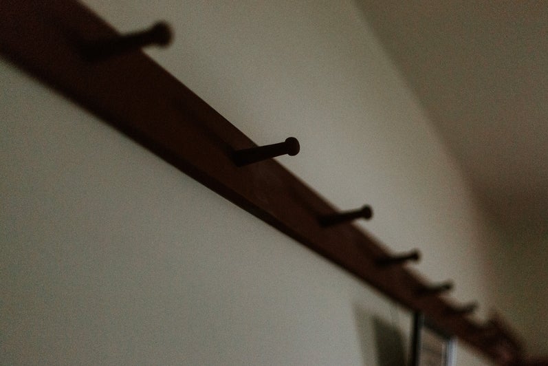 A red hat rack, made of wood runs along the wall