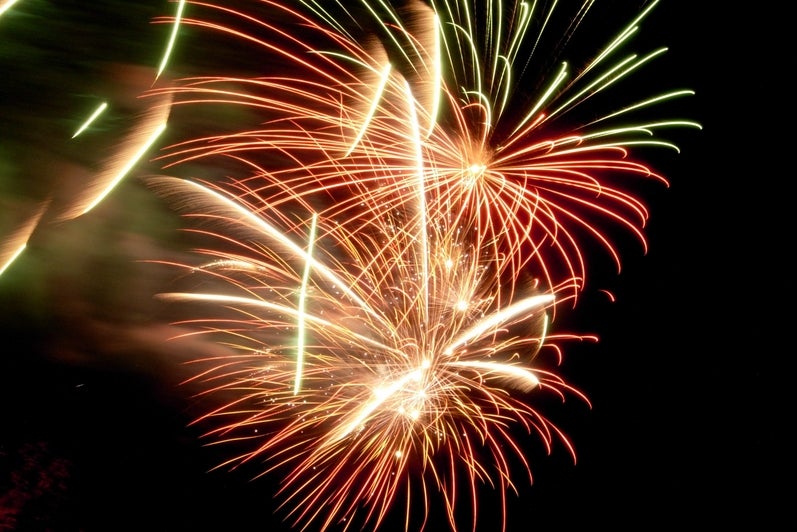 A shot of fireworks, orange and green with sparks