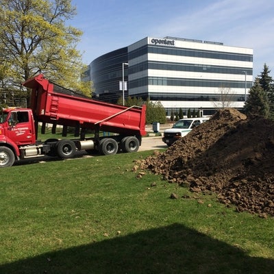 A red dumptruck prepares to carry earth away from construction