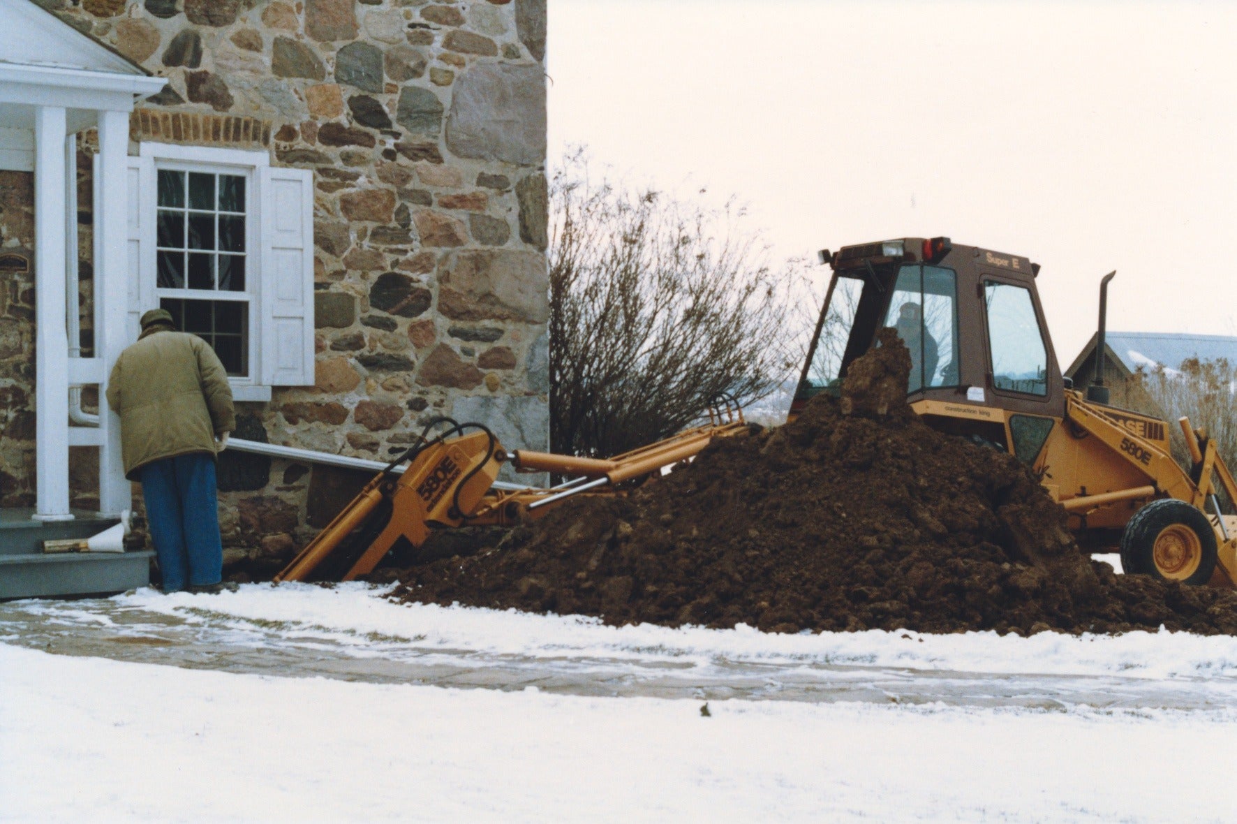 a backhoe digs into the foundation of Brubacher house for repairs